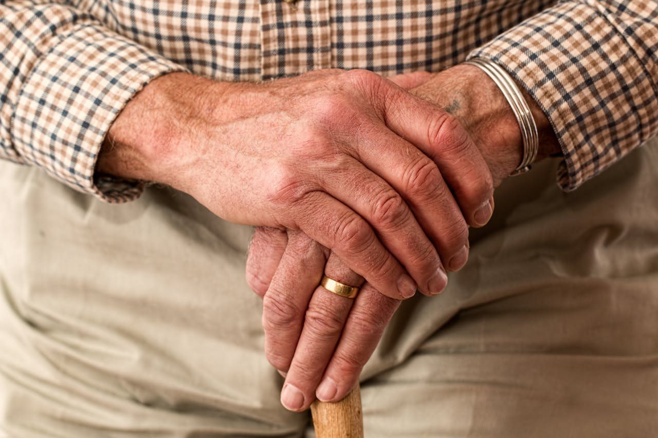 our-services-1 A detailed image of elderly hands clasping a wooden cane, symbolizing aging and support.